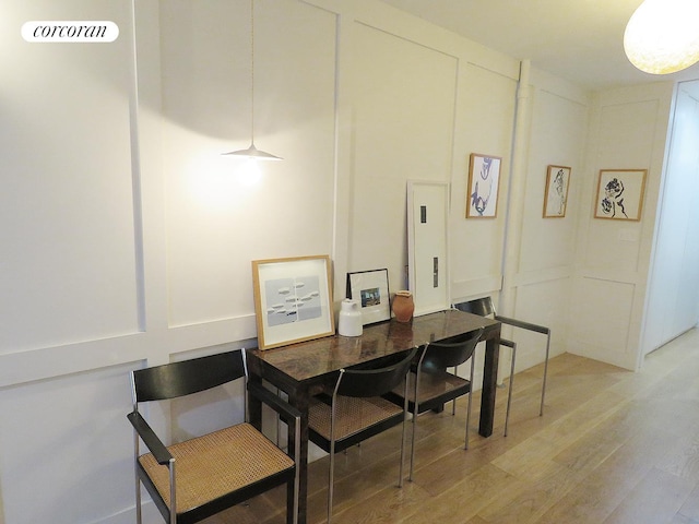 dining room featuring light wood-style floors and a decorative wall