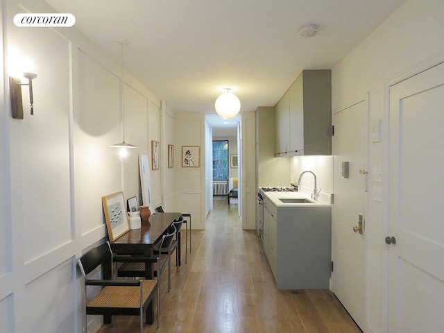 kitchen featuring visible vents, radiator, light countertops, light wood-type flooring, and a sink