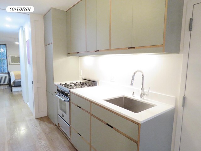 kitchen with stainless steel range, light countertops, visible vents, light wood-style flooring, and a sink