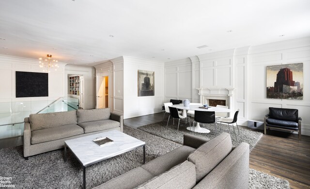 living room with a decorative wall, a fireplace, dark wood-type flooring, and crown molding