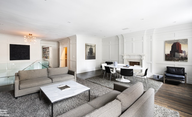 living area featuring crown molding, a decorative wall, a fireplace, and dark wood-style flooring