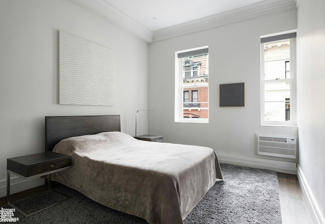 bedroom with an AC wall unit, ornamental molding, wood finished floors, and baseboards