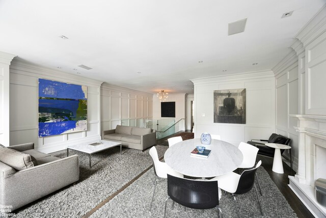 living room with dark wood finished floors, an inviting chandelier, a decorative wall, and ornamental molding