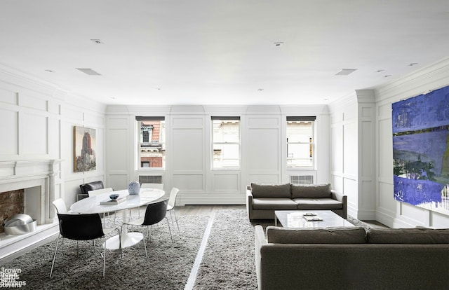 living room with crown molding, a decorative wall, a premium fireplace, and wood finished floors