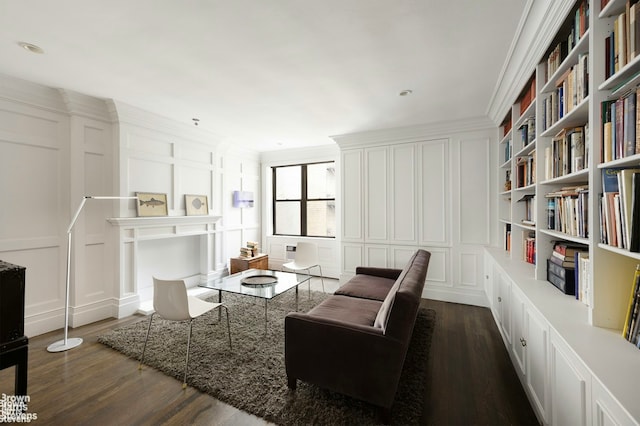 living area featuring dark wood-type flooring, crown molding, and a decorative wall