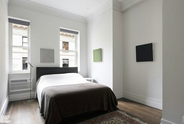 bedroom featuring a wall mounted air conditioner, crown molding, baseboards, and wood finished floors