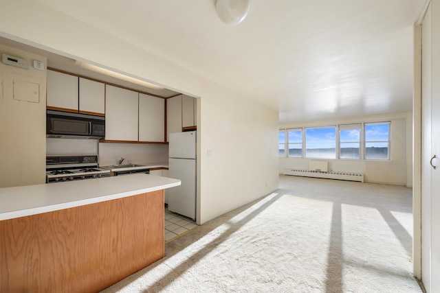 kitchen with a baseboard heating unit, white appliances, light countertops, and light carpet