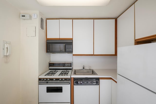 kitchen with light countertops, visible vents, white cabinets, a sink, and white appliances