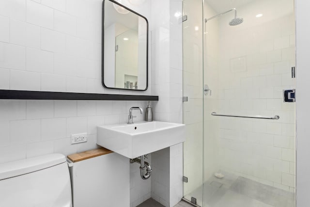 full bathroom with toilet, a stall shower, a sink, and tile walls