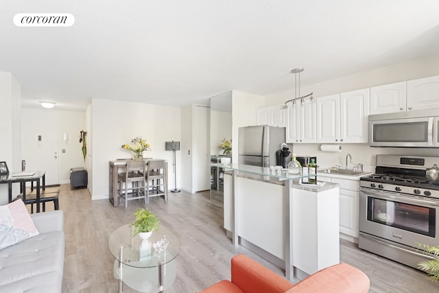 345 E 93rd St Unit 2E, New York City, NY 10128 - kitchen with appliances with stainless steel finishes, a sink, light countertops, white cabinets, and light wood-style floors