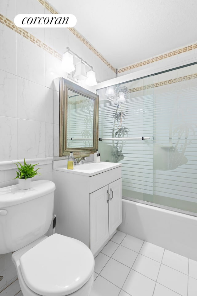 345 E 93rd St Unit 2E, New York City, NY 10128 - full bath with tile walls, tile patterned floors, toilet, vanity, and bath / shower combo with glass door