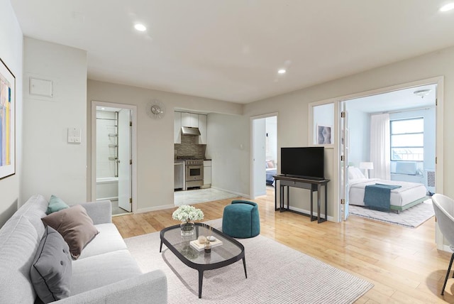 living room featuring light wood-style flooring, baseboards, and recessed lighting