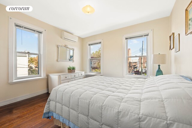 bedroom with dark wood-style flooring, a wall unit AC, visible vents, and multiple windows