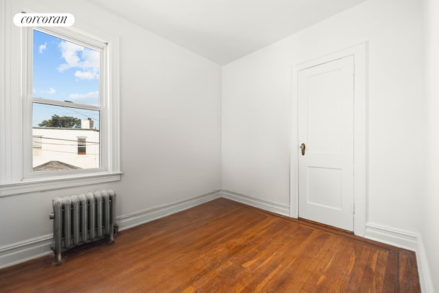 unfurnished room with baseboards, radiator heating unit, visible vents, and wood finished floors