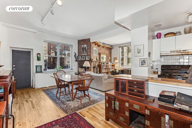 dining area featuring visible vents, light wood-style flooring, and rail lighting