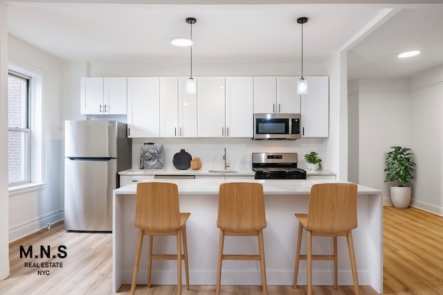 kitchen featuring appliances with stainless steel finishes, light countertops, a sink, and white cabinetry