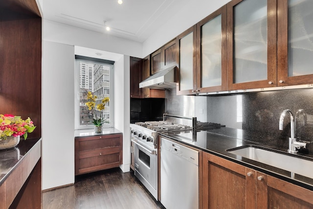 kitchen featuring dark countertops, high end stainless steel range oven, white dishwasher, a sink, and under cabinet range hood