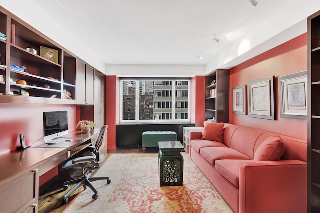 office space featuring light wood-type flooring, built in shelves, and built in study area