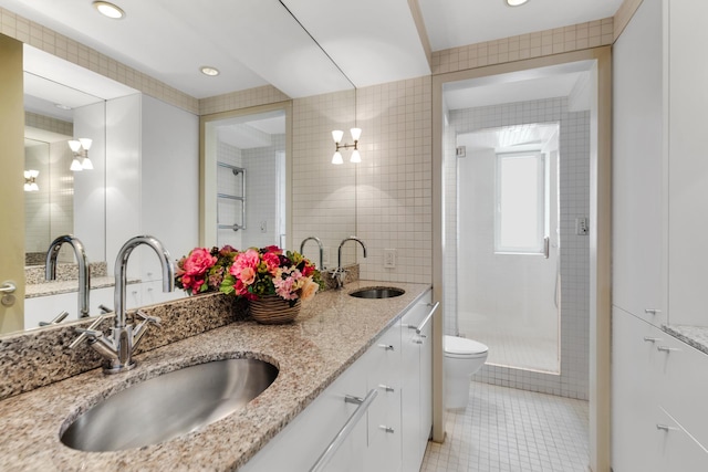 full bath with toilet, a sink, tile walls, and tile patterned floors