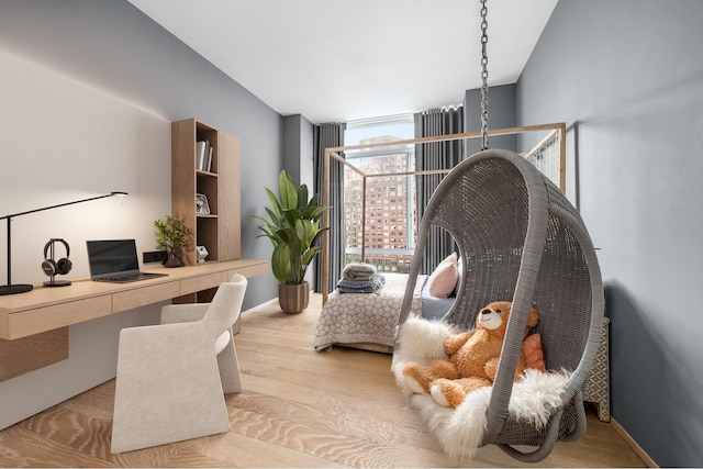 home office with floor to ceiling windows, built in desk, wood finished floors, and baseboards