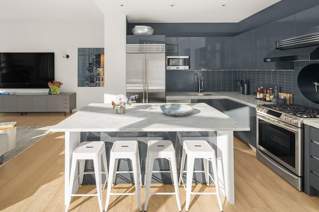 kitchen with stainless steel appliances, light wood-style flooring, a kitchen bar, and modern cabinets