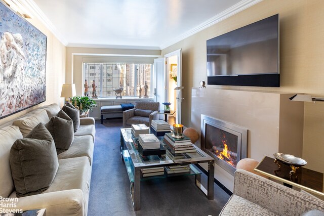 living room with a warm lit fireplace, ornamental molding, and carpet