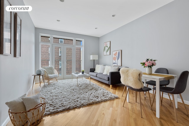 living area featuring french doors, baseboards, and light wood-style floors