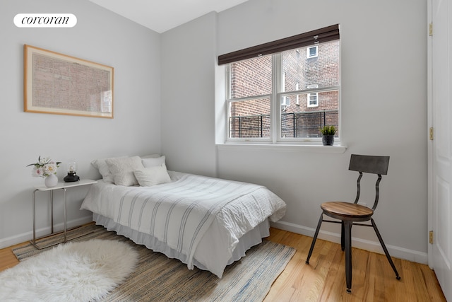 bedroom with baseboards, multiple windows, and wood finished floors