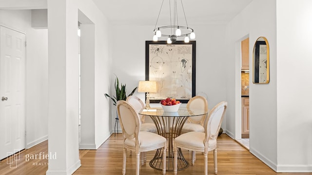 dining area with baseboards, an inviting chandelier, and light wood-style floors