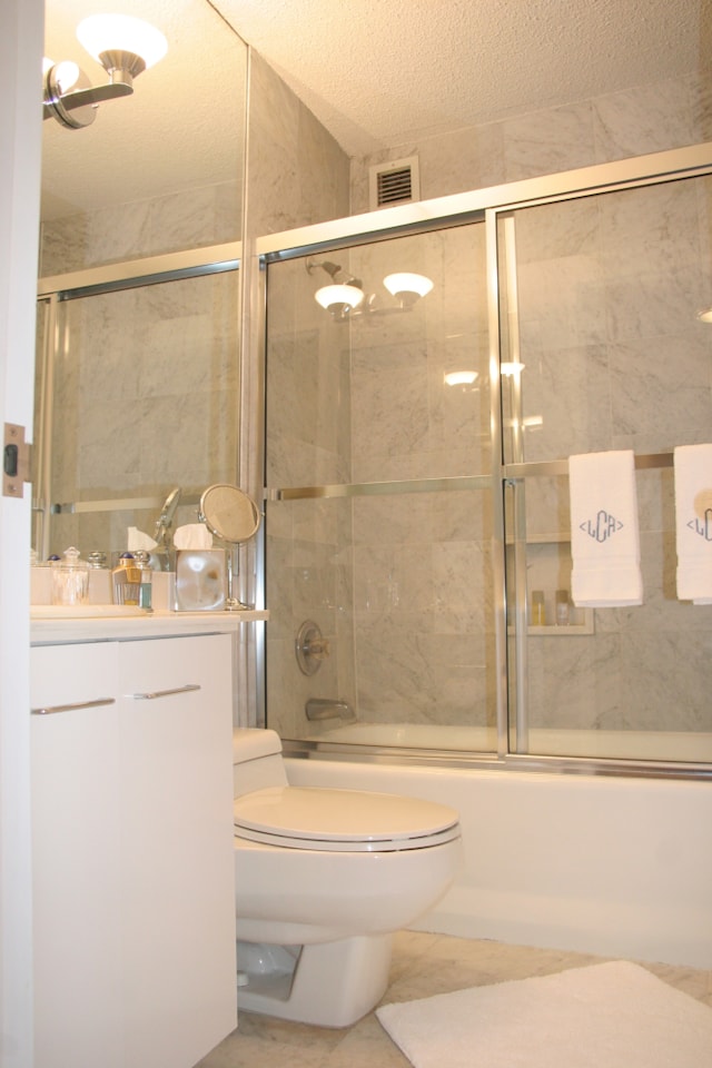 bathroom with vanity, visible vents, toilet, shower / bath combination with glass door, and a textured ceiling