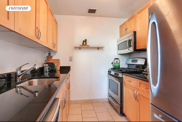 kitchen with dark countertops, visible vents, appliances with stainless steel finishes, light brown cabinets, and a sink