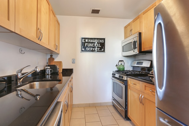 kitchen with dark countertops, visible vents, appliances with stainless steel finishes, and a sink