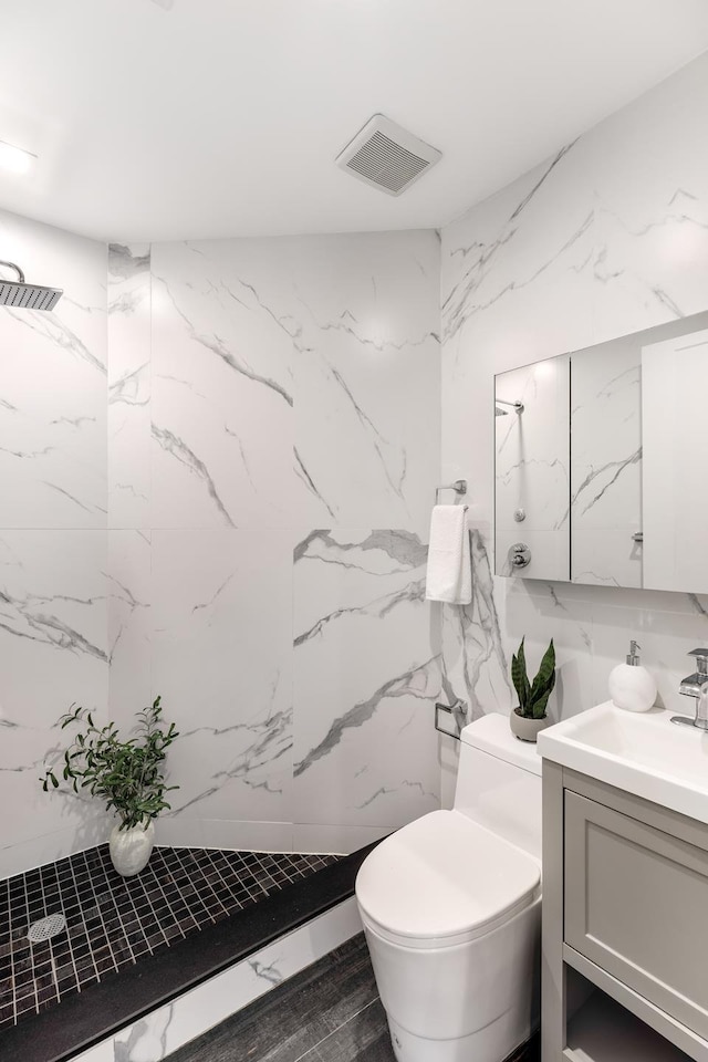 bathroom with a marble finish shower, visible vents, toilet, vanity, and stone wall