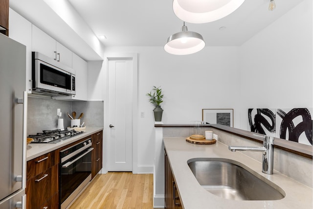 kitchen featuring tasteful backsplash, light countertops, white cabinetry, stainless steel appliances, and a sink