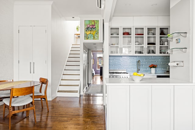 interior space with crown molding, dark wood finished floors, backsplash, a sink, and stairs