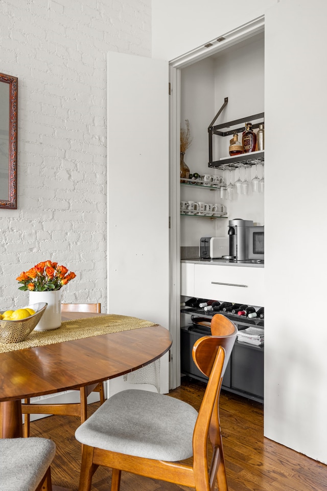 dining space with brick wall and wood finished floors