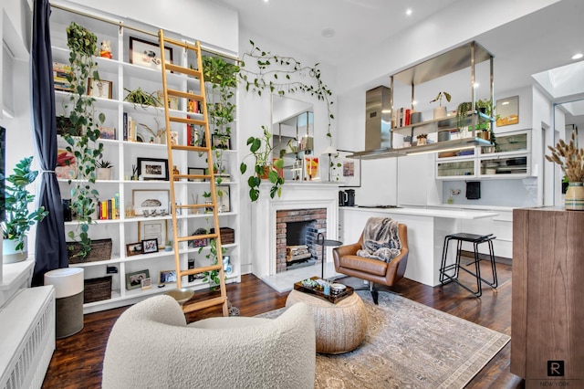 living room featuring a brick fireplace, radiator, and wood finished floors