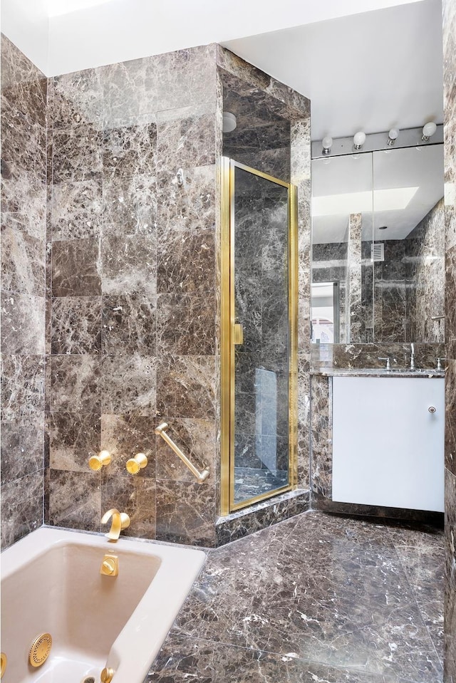 full bathroom with a whirlpool tub, a stall shower, tile walls, and vanity