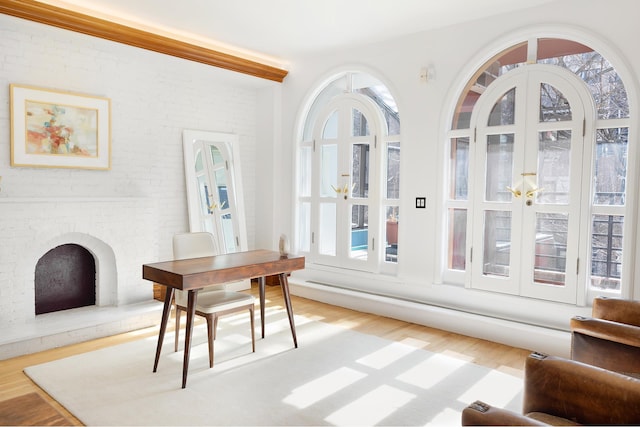 dining room featuring brick wall, plenty of natural light, and wood finished floors