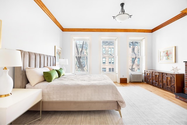 bedroom featuring multiple windows, ornamental molding, radiator heating unit, and light wood-type flooring