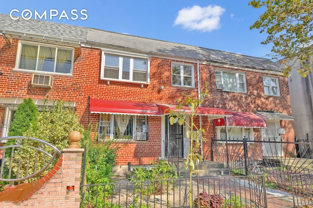 townhome / multi-family property with fence, a shingled roof, and brick siding