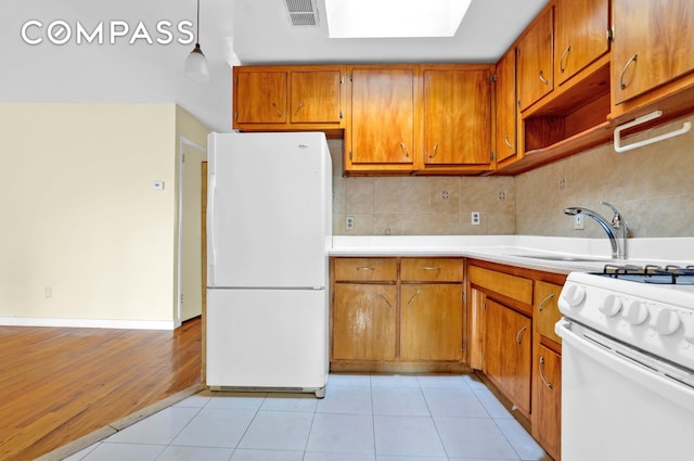 kitchen featuring brown cabinetry, backsplash, white appliances, and visible vents
