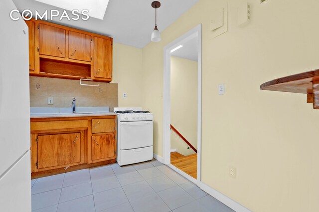 kitchen featuring decorative backsplash, white appliances, light countertops, brown cabinets, and a sink