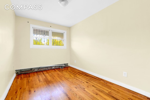 unfurnished room with baseboards, baseboard heating, and hardwood / wood-style floors
