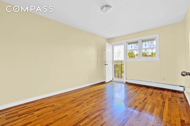 unfurnished room with baseboards, a baseboard radiator, and wood finished floors
