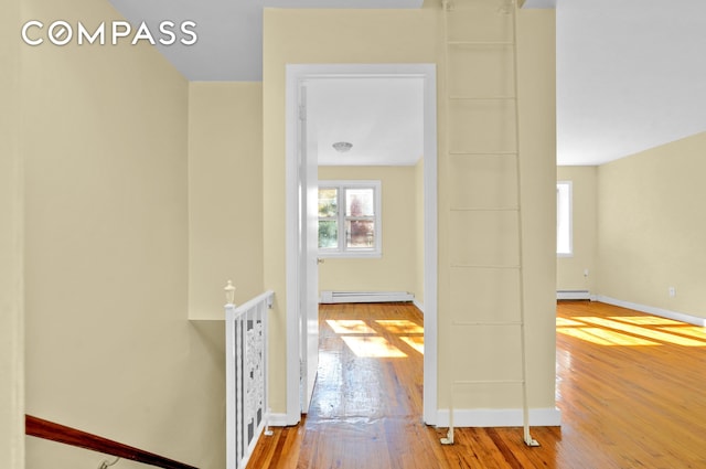hallway featuring baseboards, a baseboard heating unit, and hardwood / wood-style flooring