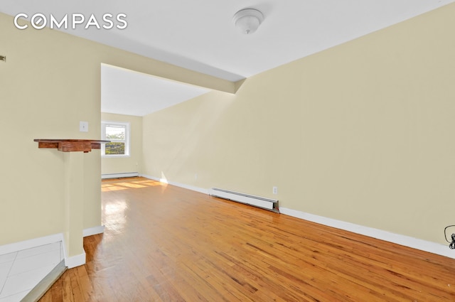 unfurnished living room featuring light wood-style flooring, beam ceiling, a baseboard heating unit, and baseboards