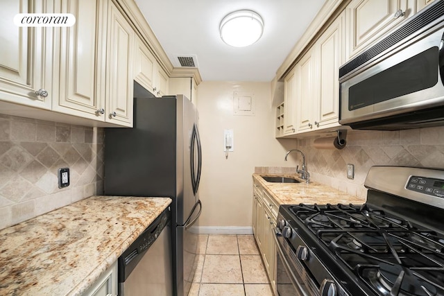 405 E 63rd St Unit 10J, New York City, NY 10065 - kitchen featuring appliances with stainless steel finishes, cream cabinetry, a sink, baseboards, and tasteful backsplash