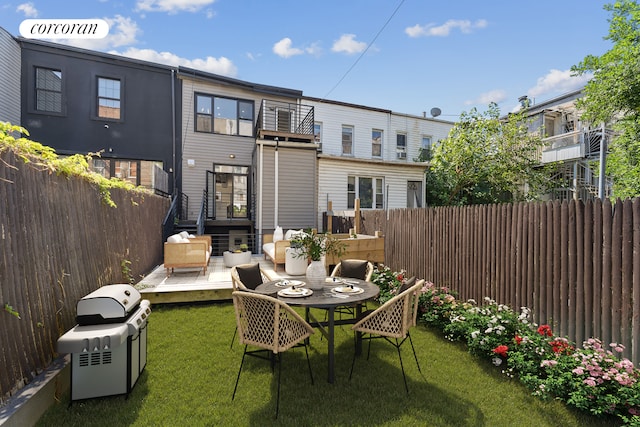 rear view of property with a deck, a yard, fence, and a balcony