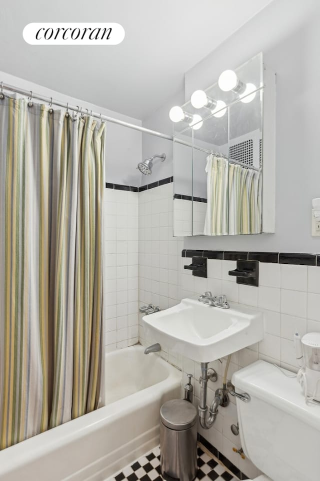 full bathroom featuring shower / tub combo, toilet, and tile walls